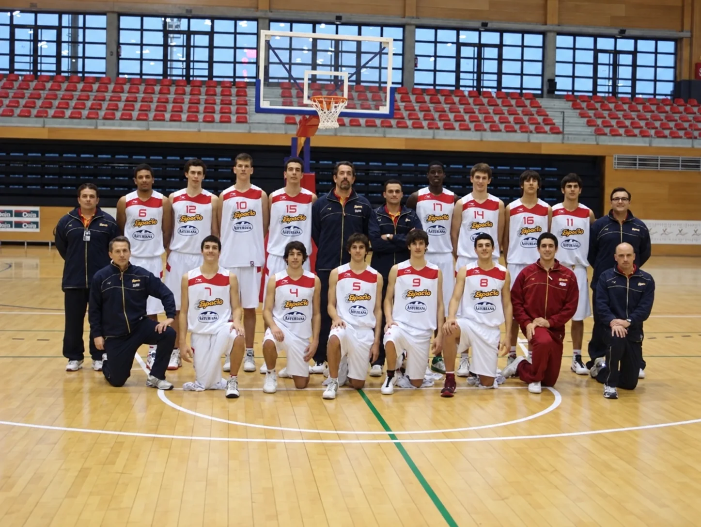 Fotografía de grupo de un equipo de baloncesto con jugadores y cuerpo técnico en chándal oscuro